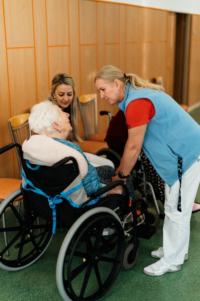 Crafting Captivating Headlines: Your awesome post title goes here A caregiver talks with elderly women in a wheelchair at a retirement home.