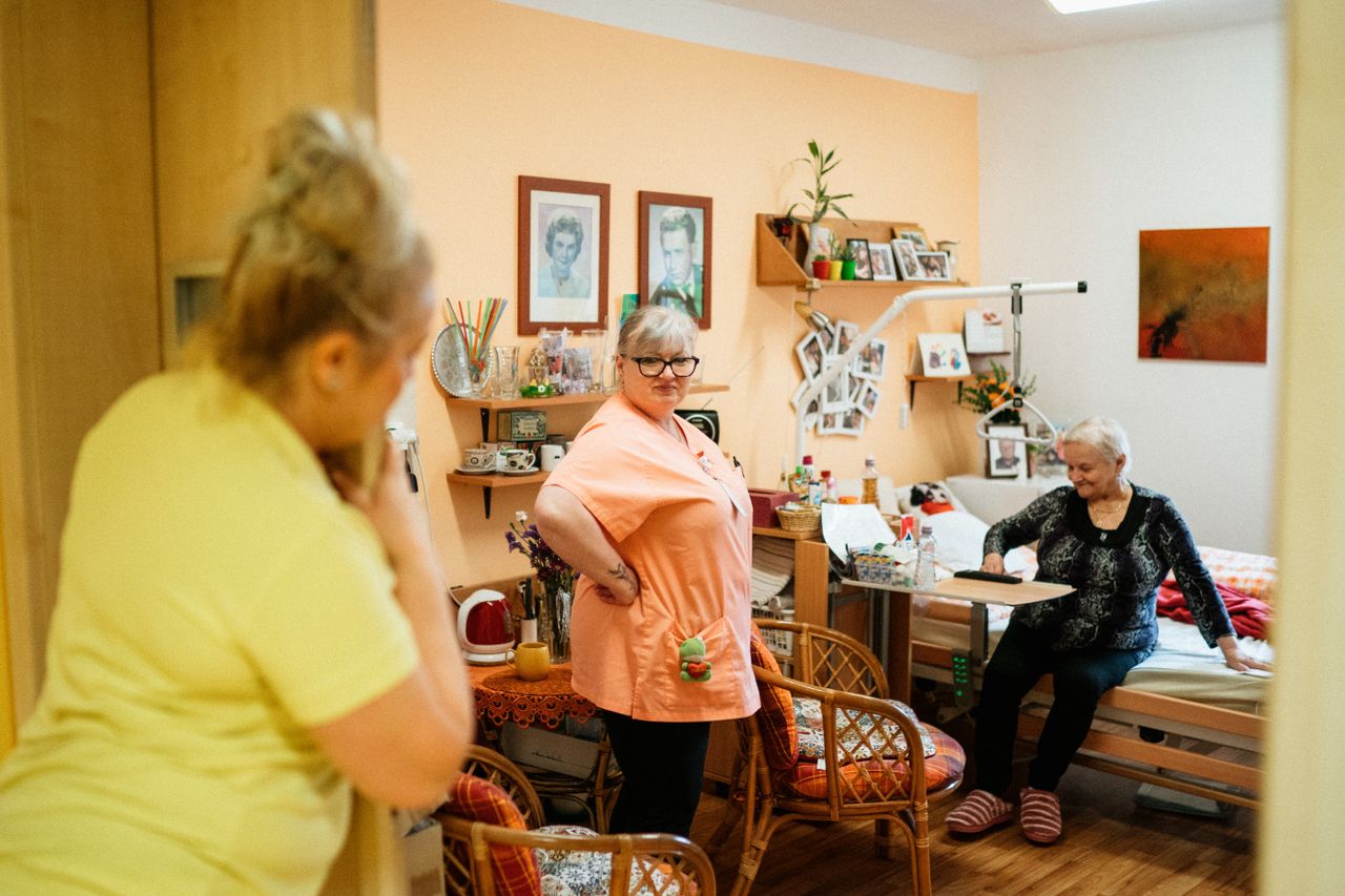 Services Caregivers interacting with a senior woman in a cozy retirement home in Karviná, Czech Republic.